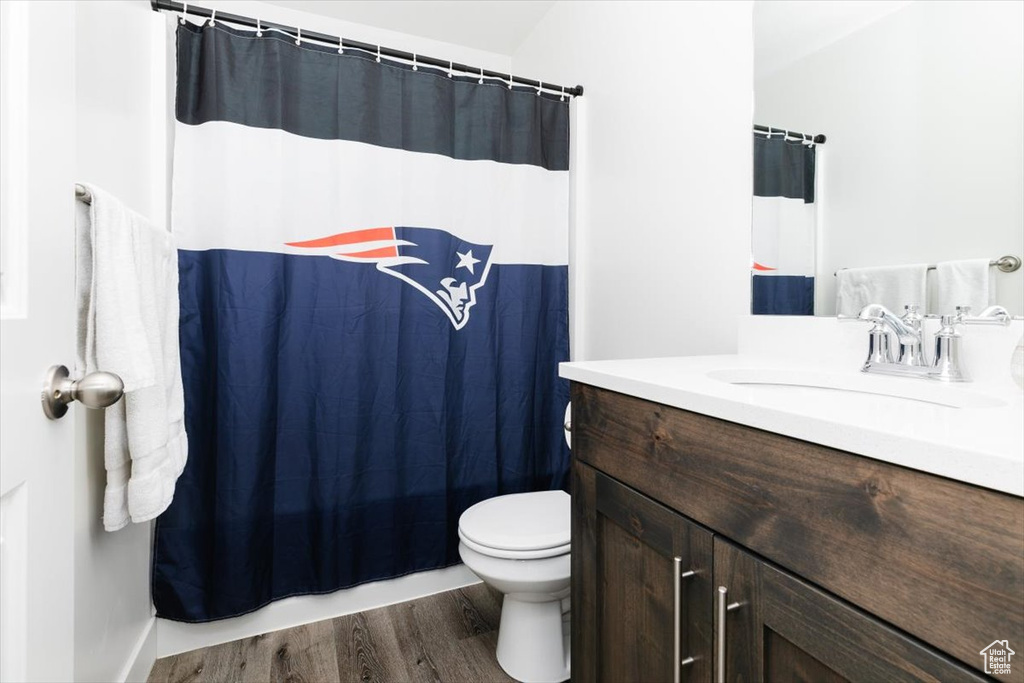 Bathroom with vanity, wood finished floors, toilet, and a shower with curtain