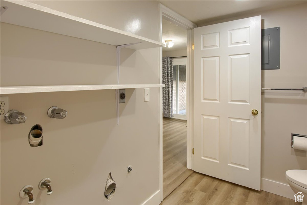 Bathroom with baseboards, toilet, electric panel, and wood finished floors