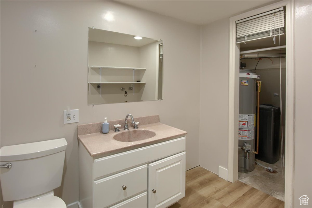 Bathroom with water heater, toilet, wood finished floors, and vanity