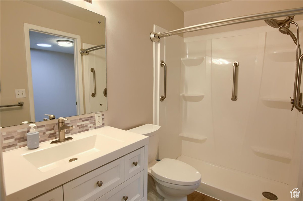 Full bathroom featuring a stall shower, vanity, toilet, and backsplash