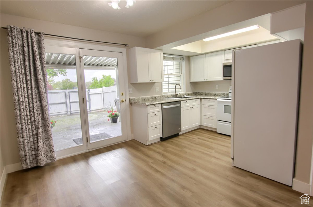 Kitchen featuring light wood finished floors, stainless steel appliances, white cabinets, and a sink