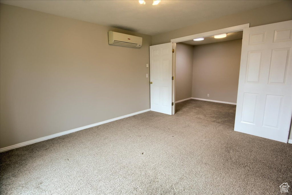 Spare room featuring a wall mounted AC, baseboards, and carpet