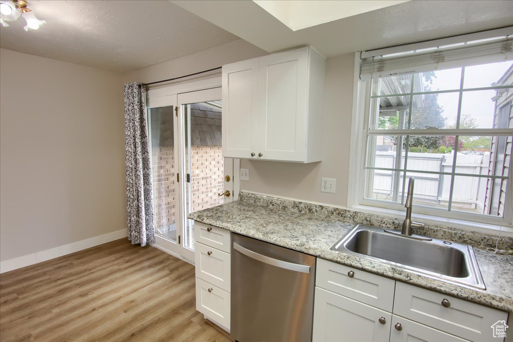 Kitchen featuring white cabinetry, light wood-style floors, a sink, and dishwasher