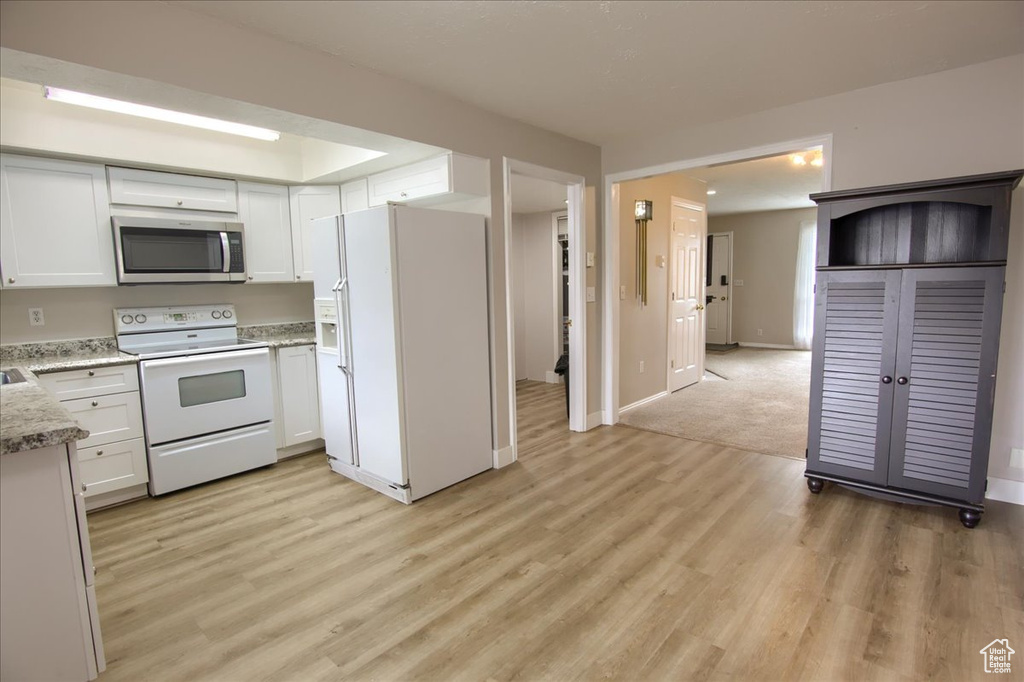 Kitchen with white cabinetry, white appliances, baseboards, and light wood-type flooring