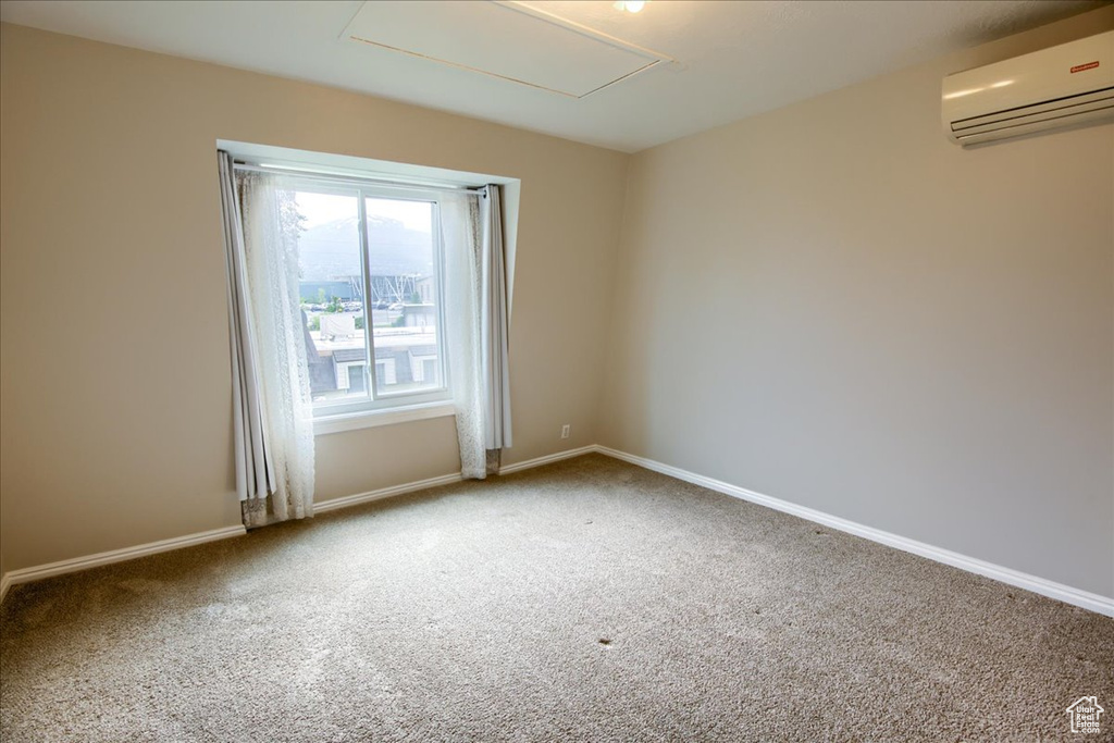 Spare room featuring baseboards, a wall unit AC, and carpet