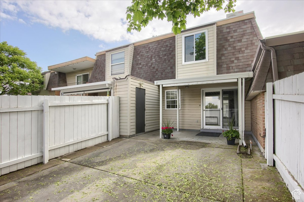 Back of property featuring roof with shingles, fence, a patio, and mansard roof