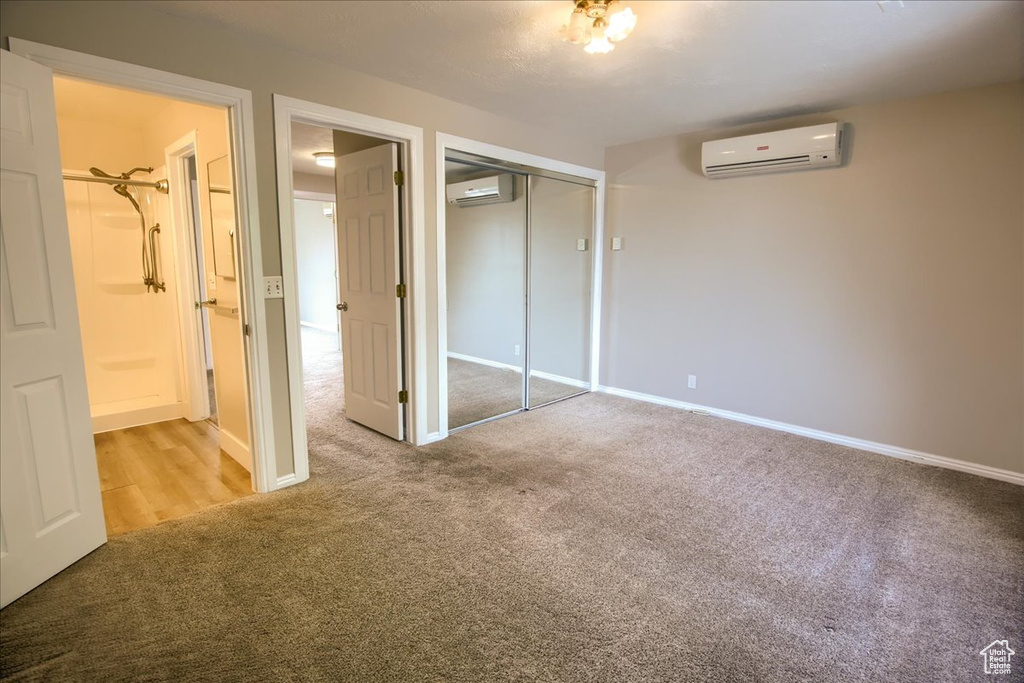 Unfurnished bedroom featuring a closet, baseboards, a wall unit AC, and carpet floors