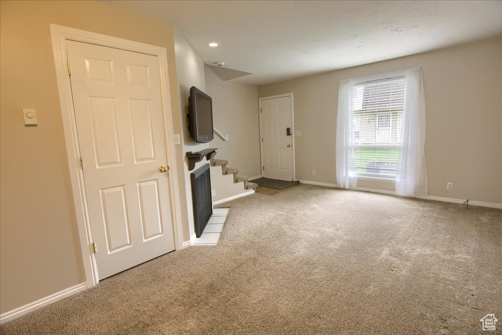 Unfurnished living room with stairway, carpet flooring, and baseboards