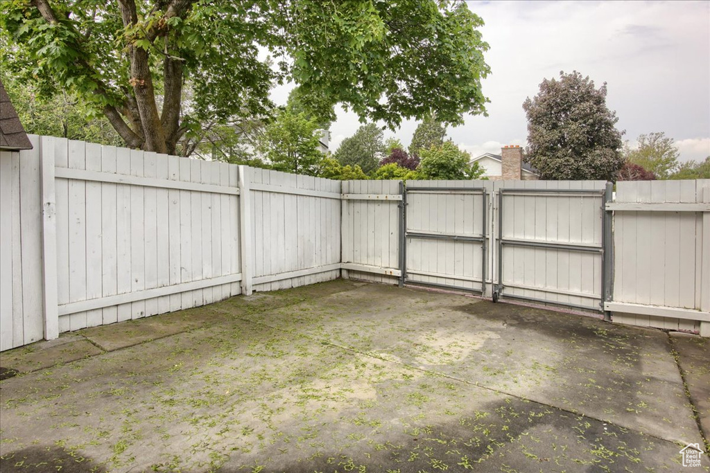View of gate with a patio area and a fenced backyard