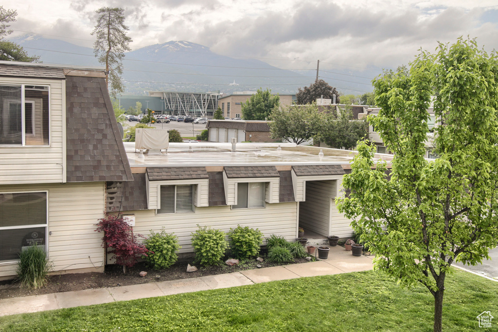 View of front of house with a front yard, a mountain view, and roof with shingles