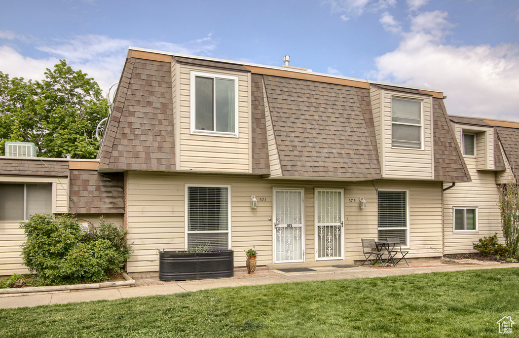 Back of house featuring a shingled roof, mansard roof, a yard, and a patio area