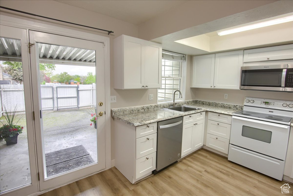Kitchen featuring a sink, stainless steel appliances, white cabinetry, and light wood-type flooring