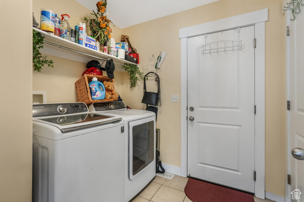 Clothes washing area featuring washing machine and clothes dryer, light tile patterned flooring, and laundry area