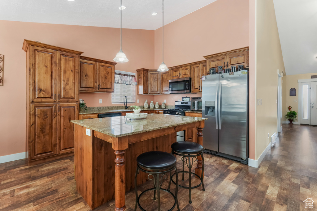 Kitchen featuring brown cabinetry, stainless steel appliances, high vaulted ceiling, and dark wood-style floors
