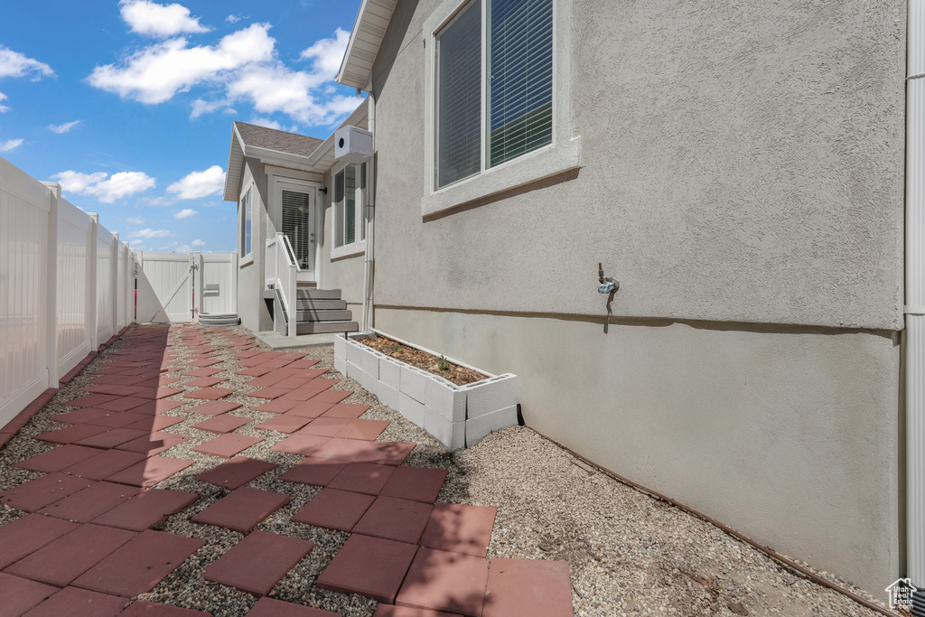 View of property exterior with a patio, stucco siding, fence, and a gate