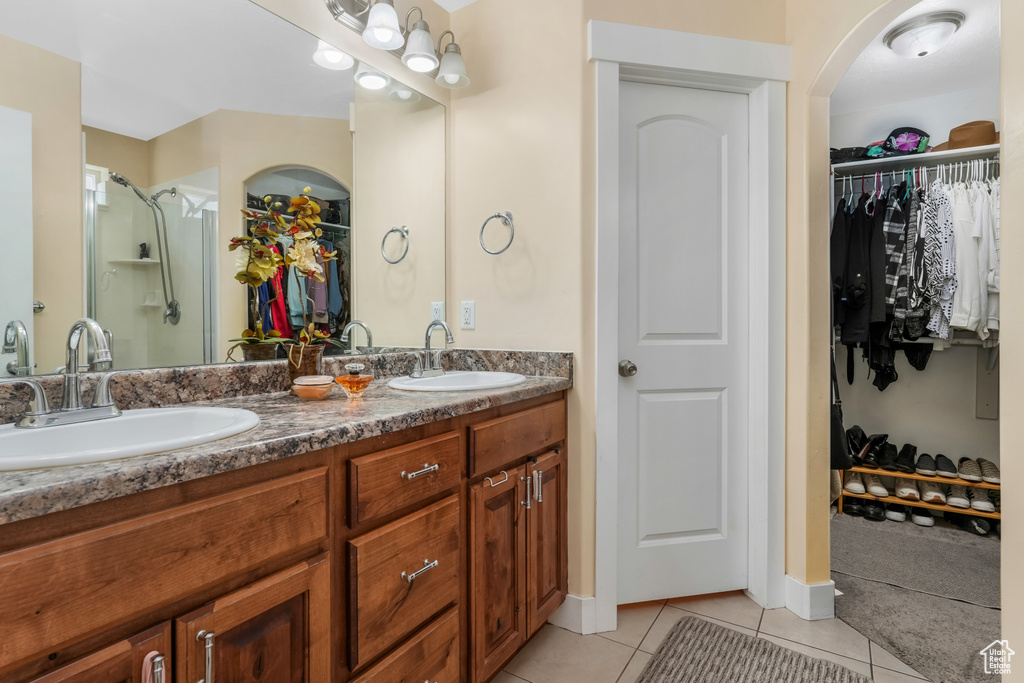 Full bath featuring a sink, double vanity, a spacious closet, and tile patterned floors