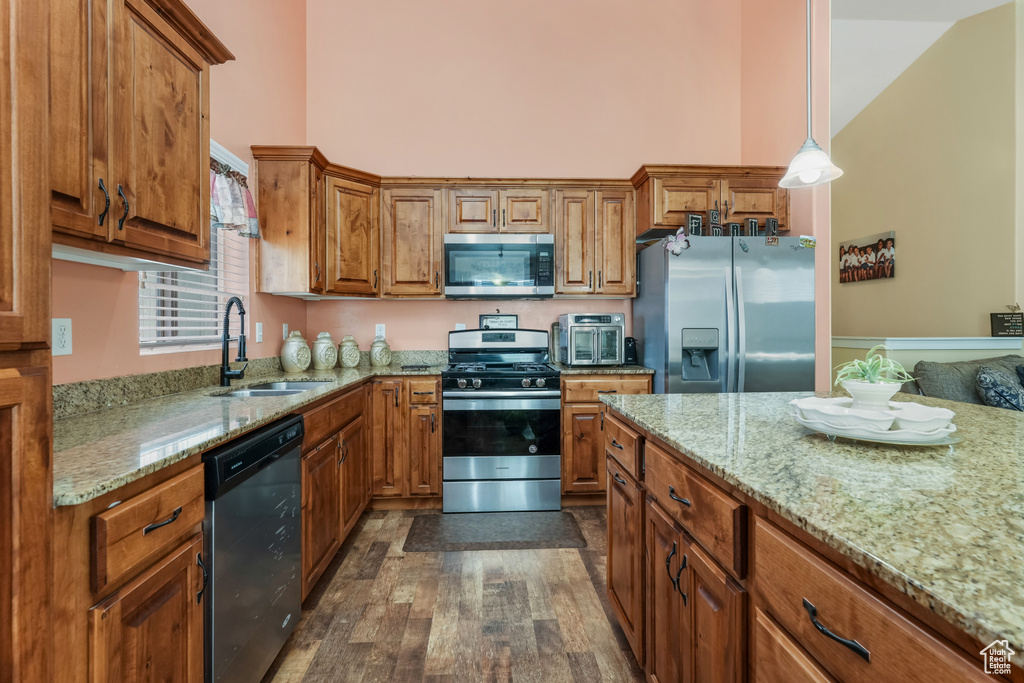 Kitchen featuring a sink, brown cabinetry, stainless steel appliances, and a high ceiling