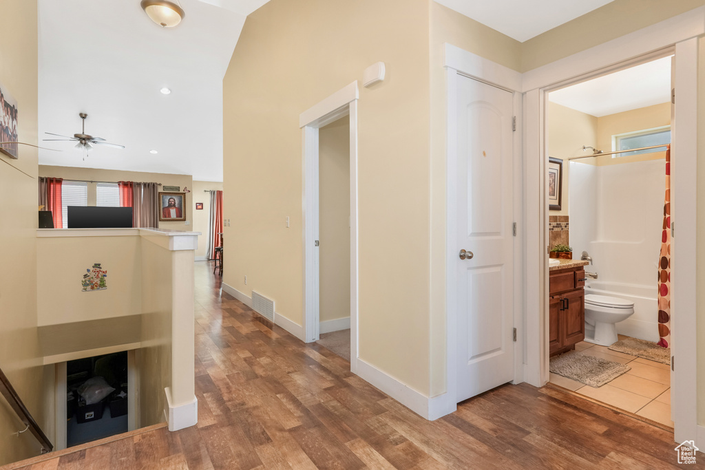 Hallway with visible vents, wood finished floors, and baseboards