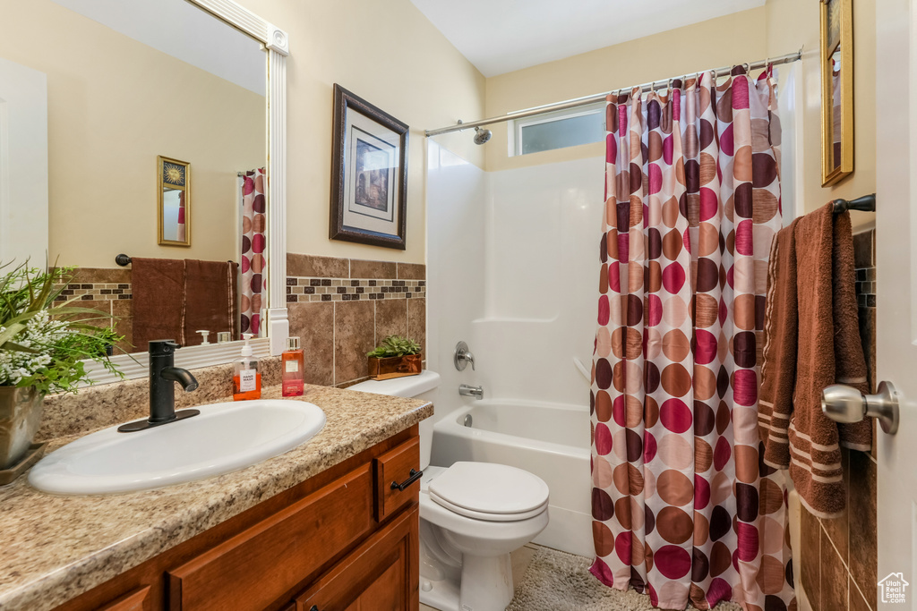 Bathroom with toilet, a wainscoted wall, tile walls, shower / bathtub combination with curtain, and vanity