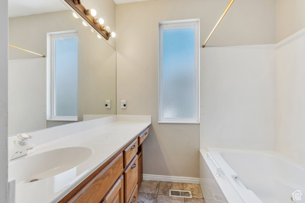 Full bath featuring baseboards, visible vents, a bathing tub, and vanity