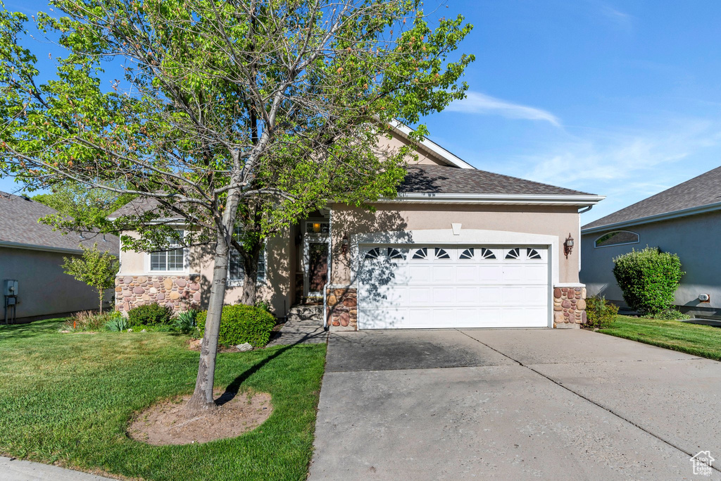 Obstructed view of property featuring stone siding, stucco siding, a front yard, and driveway