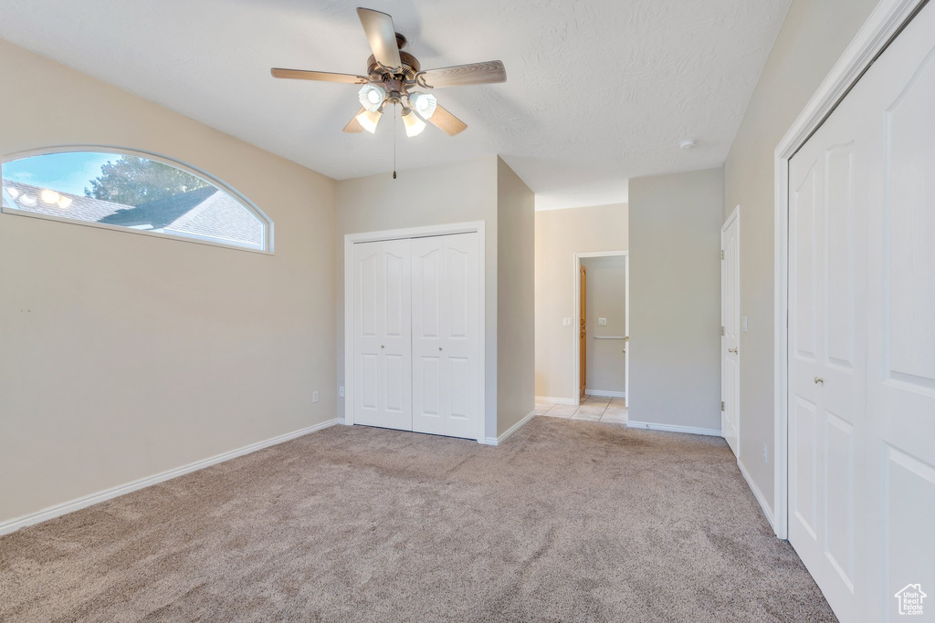 Unfurnished bedroom with light carpet, baseboards, and a ceiling fan