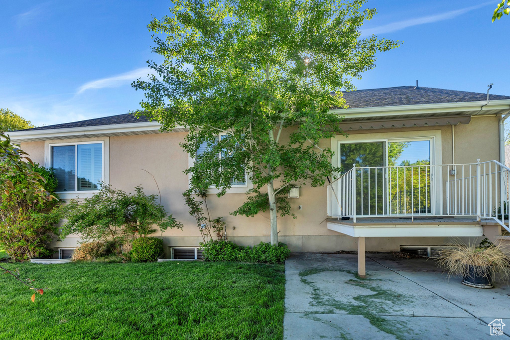 View of home\\\'s exterior featuring a yard, stucco siding, and roof with shingles