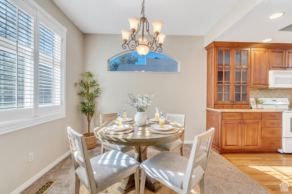 Dining room with recessed lighting, baseboards, a healthy amount of sunlight, and a notable chandelier