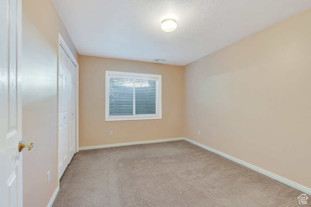 Unfurnished bedroom with carpet, a closet, baseboards, and visible vents