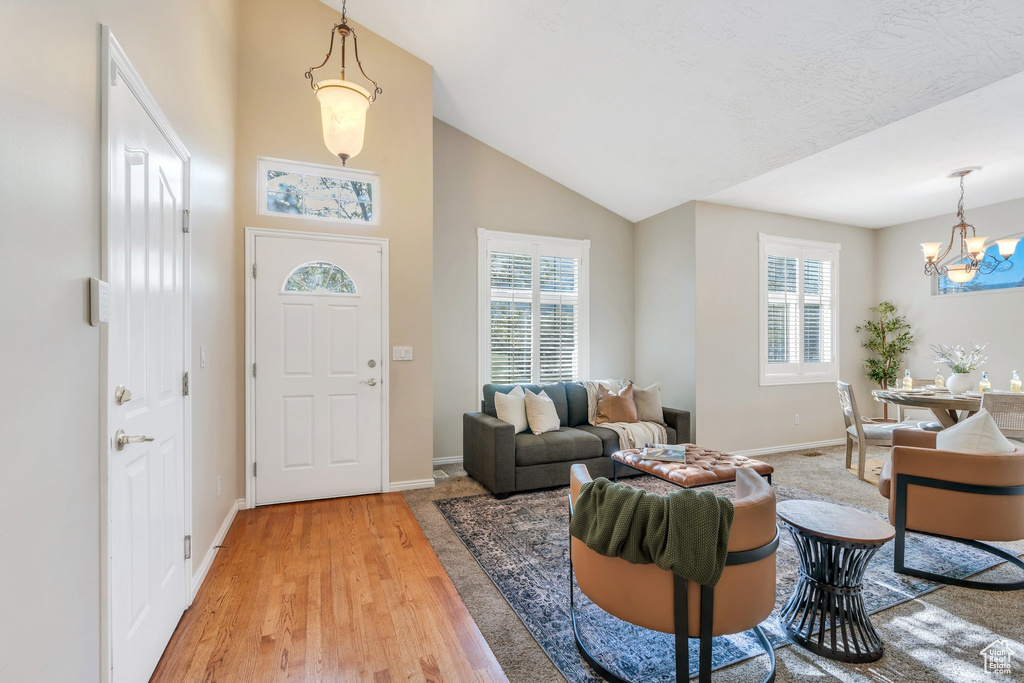 Foyer with light wood finished floors, a notable chandelier, baseboards, and plenty of natural light