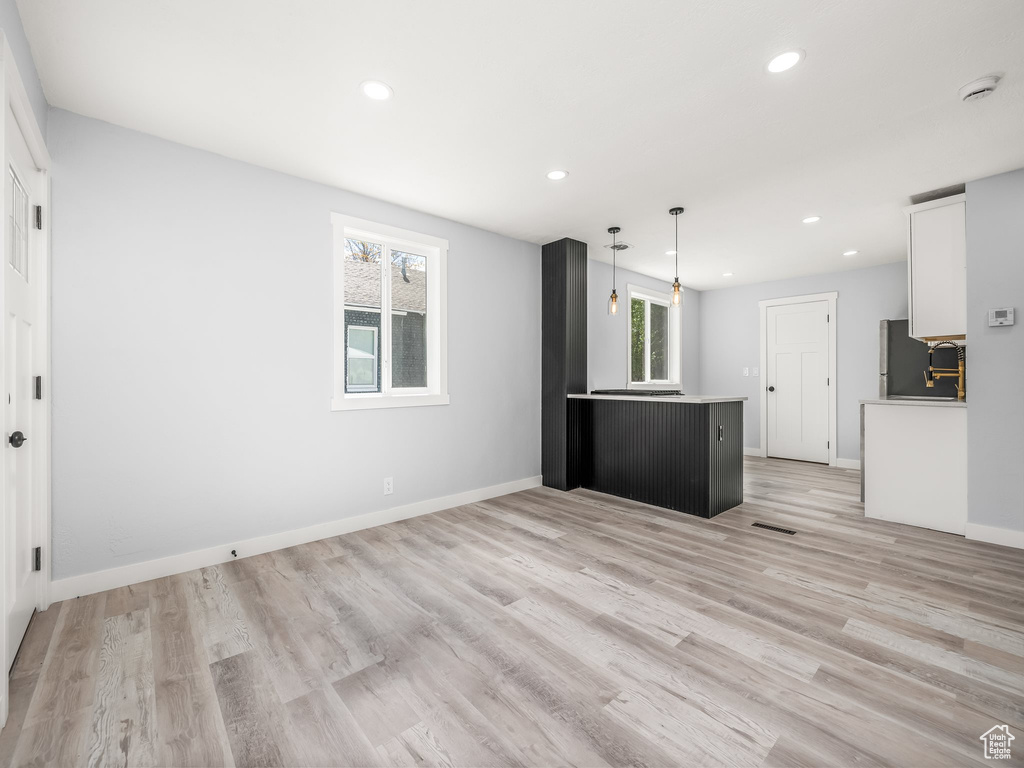 Kitchen with fridge, light wood-style floors, white cabinets, and recessed lighting