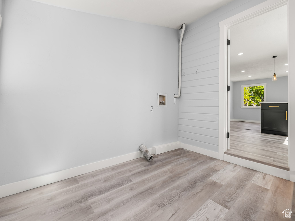 Clothes washing area with laundry area, light wood-style flooring, baseboards, and washer hookup