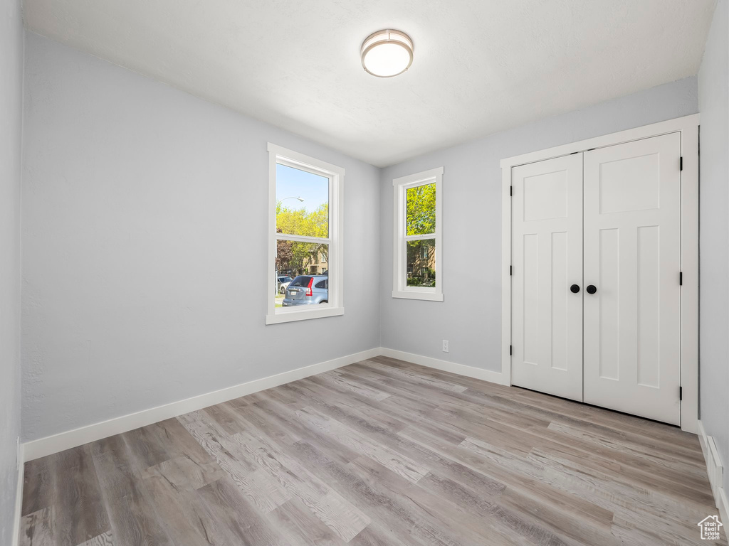 Unfurnished bedroom featuring a closet, light wood-type flooring, and baseboards