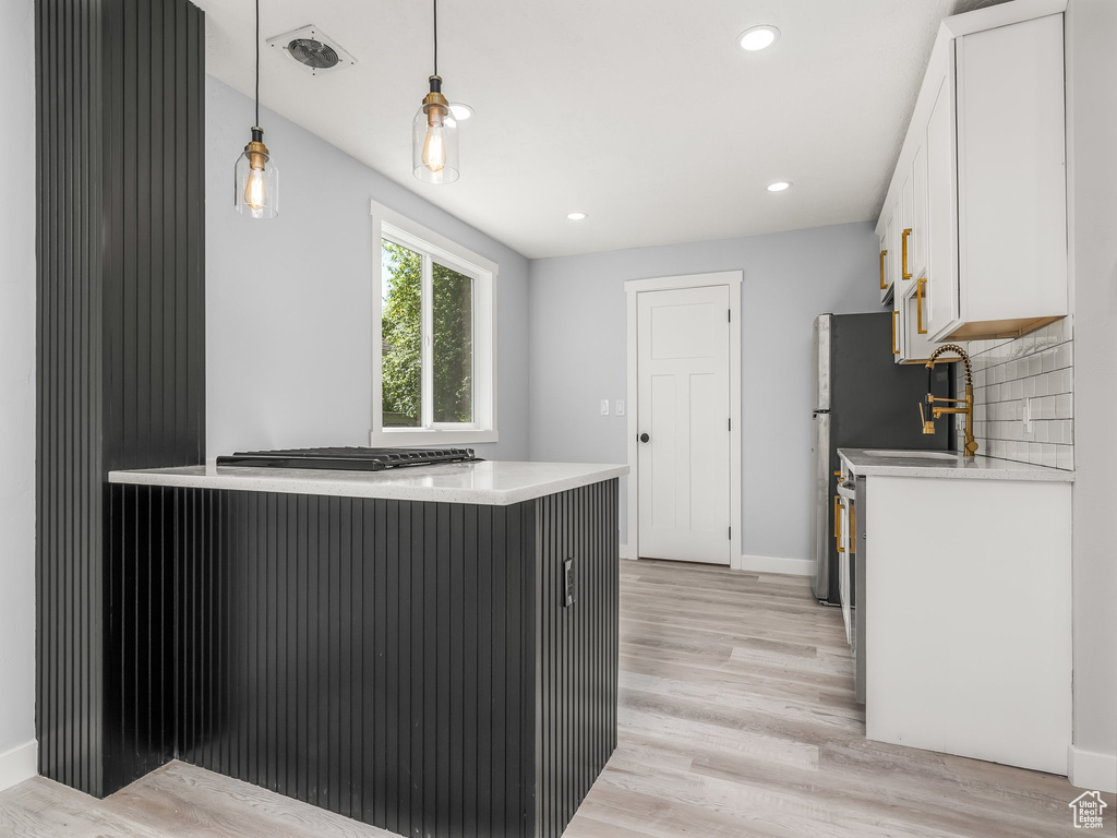 Kitchen featuring light wood finished floors, white cabinetry, and light countertops