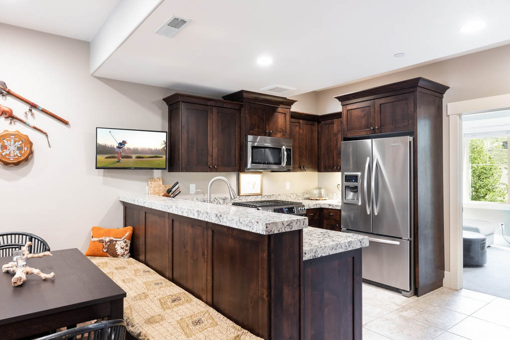 Kitchen with a peninsula, dark brown cabinetry, appliances with stainless steel finishes, and light tile patterned floors