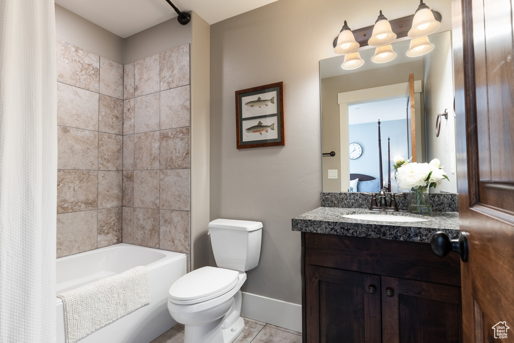 Full bath with tile patterned flooring, vanity, toilet, shower / bath combo with shower curtain, and baseboards