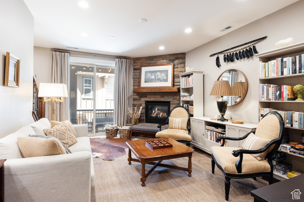 Living room with recessed lighting, visible vents, a stone fireplace, and wood finished floors