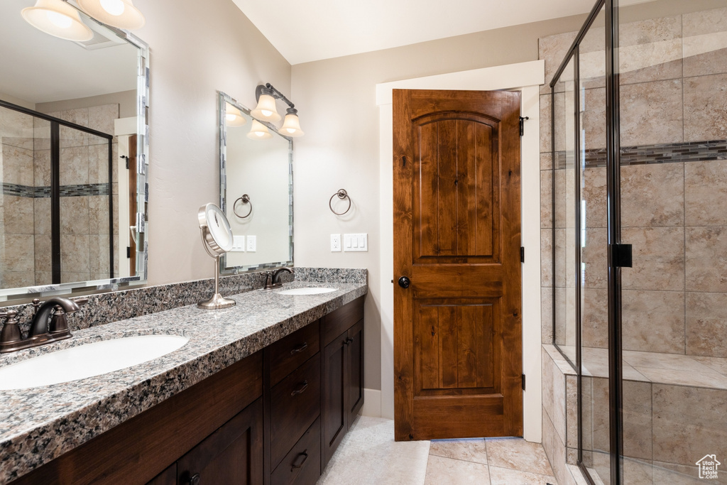 Full bath featuring double vanity, a sink, tile patterned floors, and a shower stall
