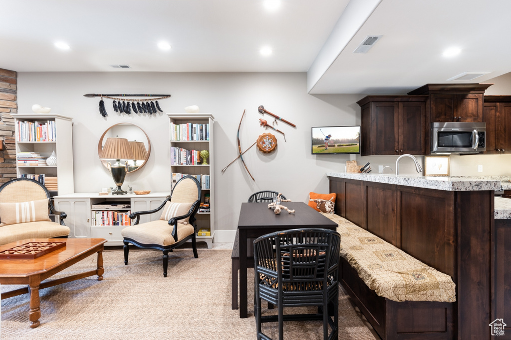 Interior space featuring visible vents, light colored carpet, dark brown cabinets, stainless steel microwave, and recessed lighting