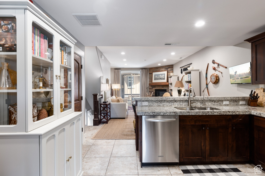Kitchen with dark brown cabinets, a sink, dishwasher, a peninsula, and visible vents
