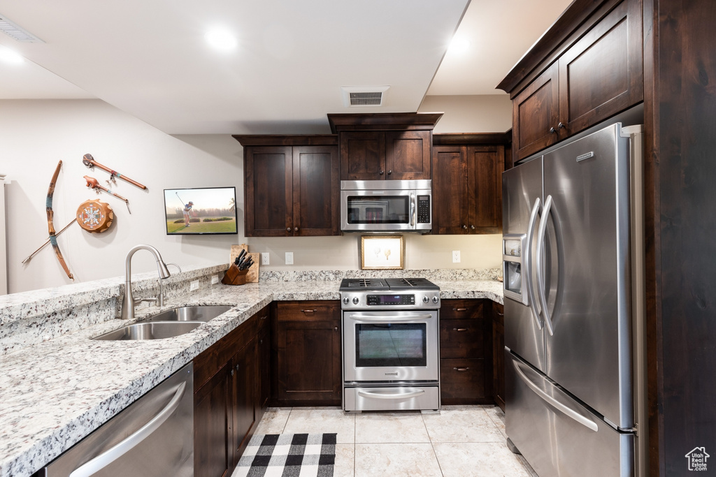 Kitchen with visible vents, a sink, appliances with stainless steel finishes, and dark brown cabinetry
