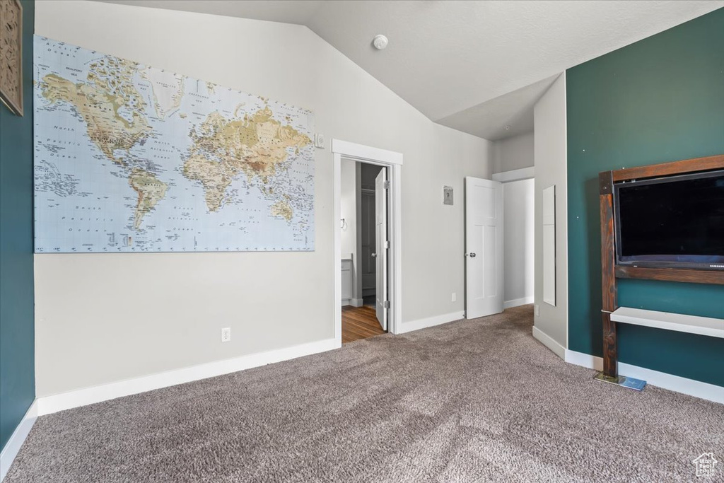 Unfurnished bedroom featuring carpet flooring, vaulted ceiling, and baseboards