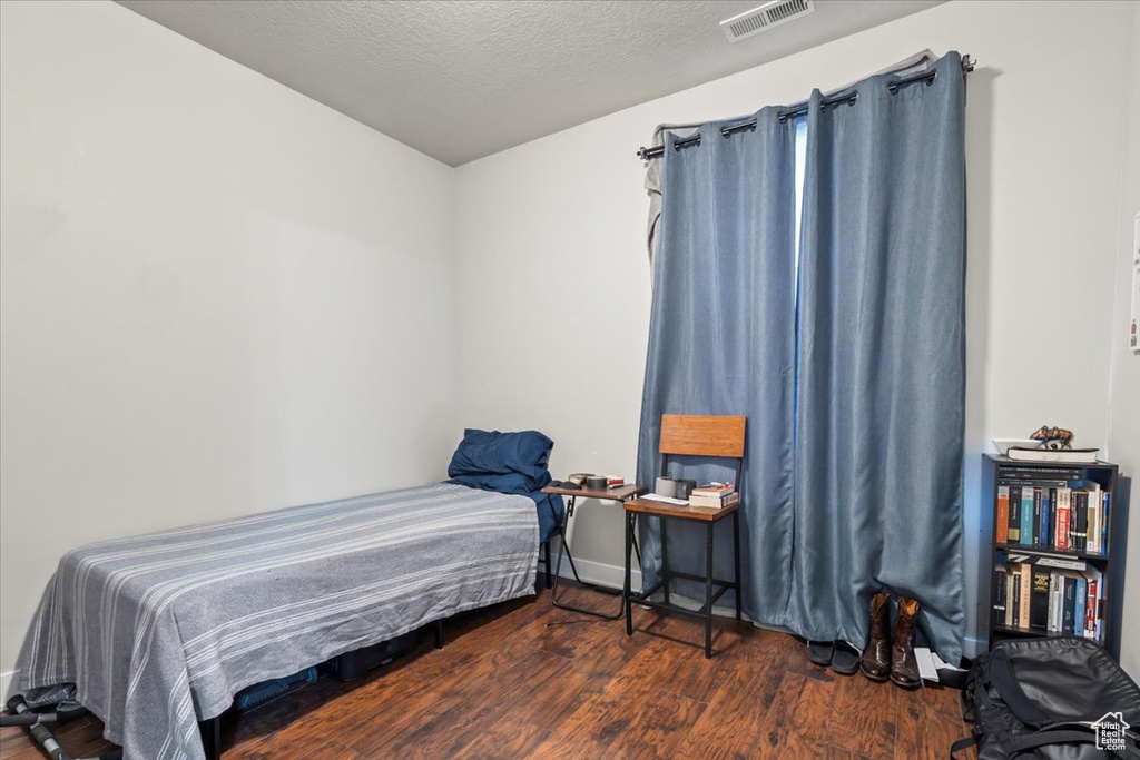 Bedroom with baseboards, visible vents, and wood finished floors