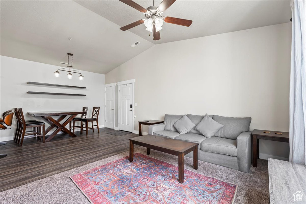 Living room with wood finished floors, visible vents, vaulted ceiling, ceiling fan, and baseboards