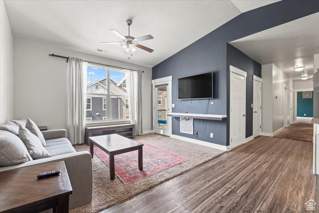 Living area with lofted ceiling, ceiling fan, a textured ceiling, and wood finished floors