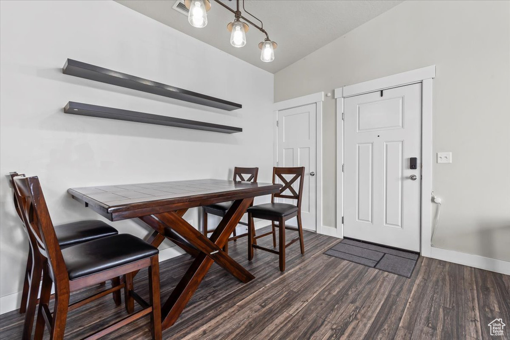 Dining room featuring baseboards, lofted ceiling, and dark wood-style floors