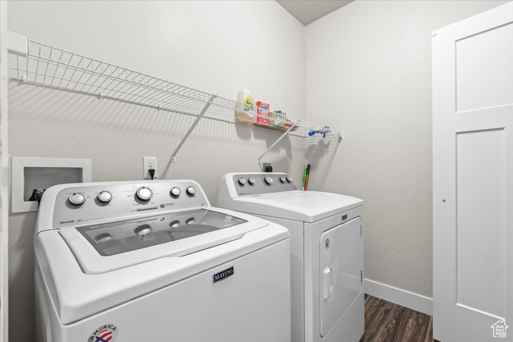 Clothes washing area with washing machine and dryer, laundry area, dark wood-style flooring, and baseboards