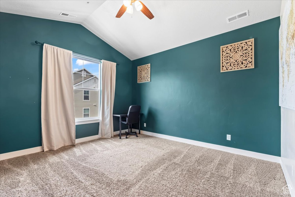 Carpeted spare room featuring baseboards, visible vents, lofted ceiling, and a ceiling fan