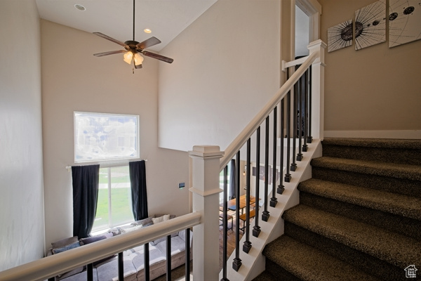 Staircase featuring high vaulted ceiling, a ceiling fan, and recessed lighting