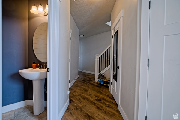 Hallway with wood finished floors, baseboards, a sink, and a textured ceiling